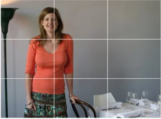 An image of a woman standing next to a table with lines added to the image to demonstrate the rule of thirds.
